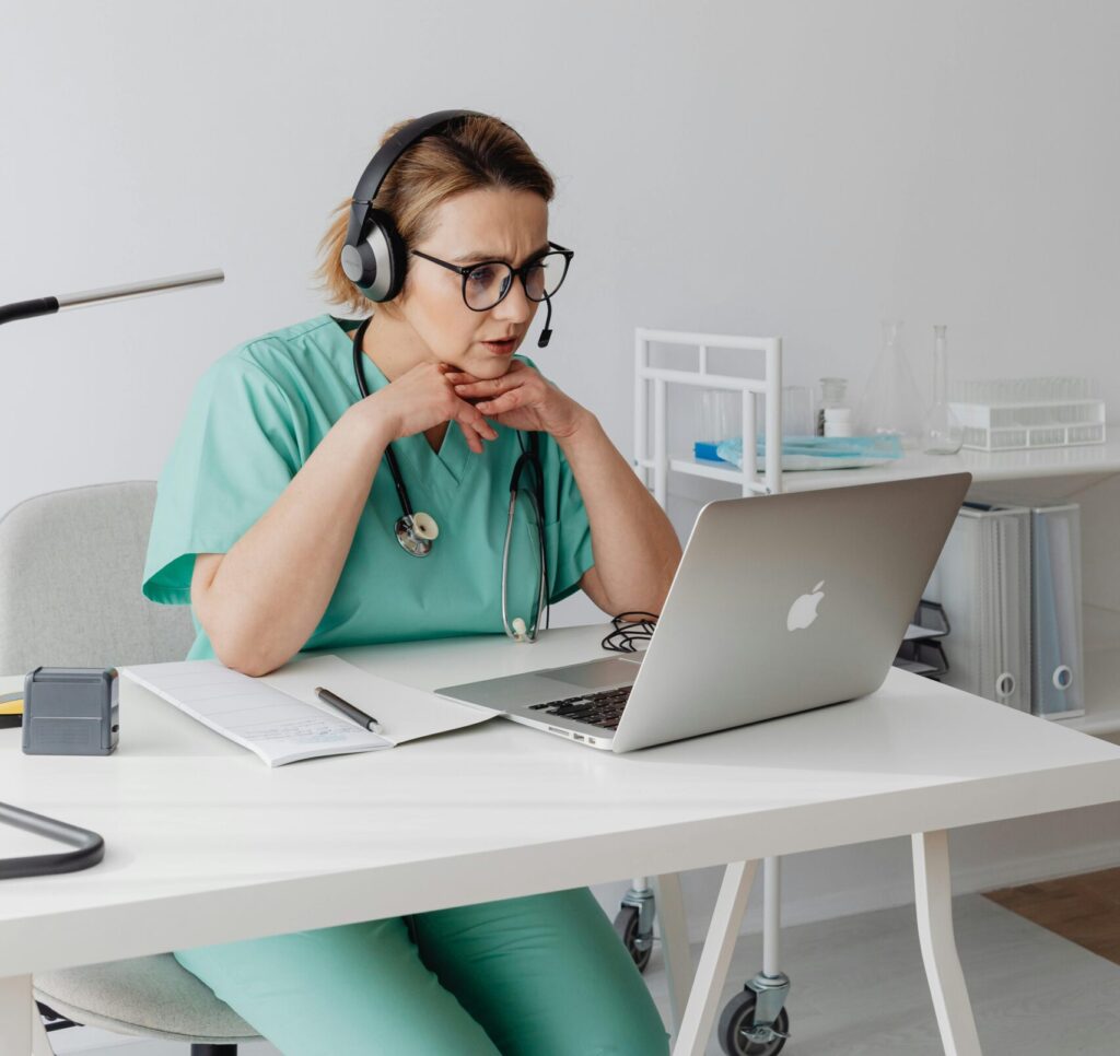 pexels photo 7195437 7195437 A medical professional focuses intently on a laptop while wearing teal scrubs and headphones.